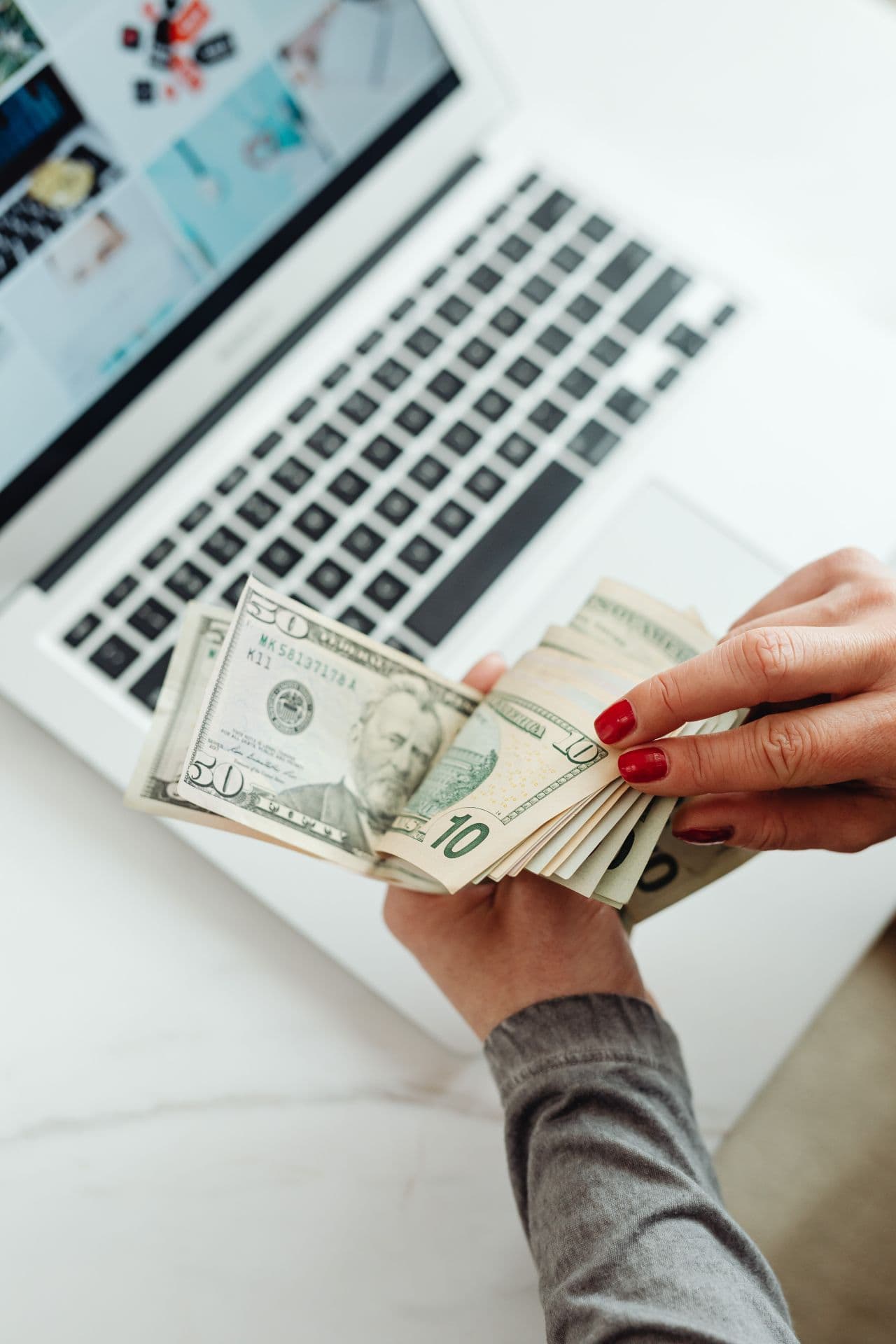 Hands counting U.S. dollar bills over a laptop during a financing review