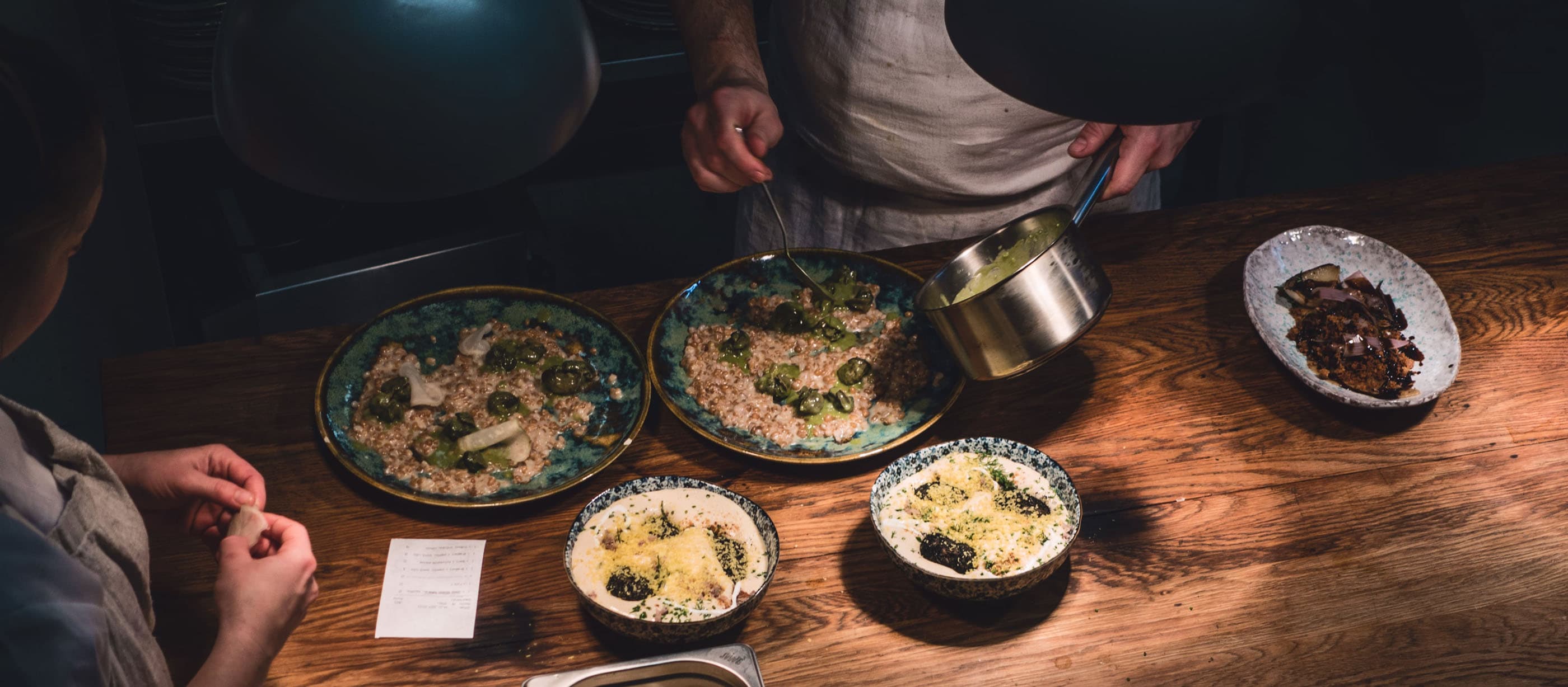 Chefs plating dishes on the pass of an open commercial restaurant kitchen
